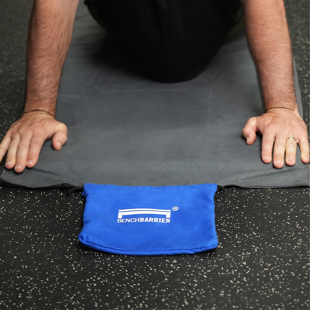 Gray yoga towel with cobalt storage pouch being used on a mat